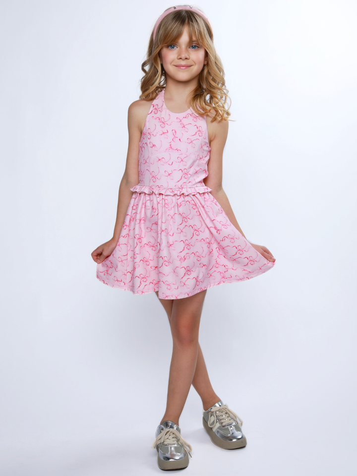 Girl wearing pink bow print dress with halter neck and ruffle waist