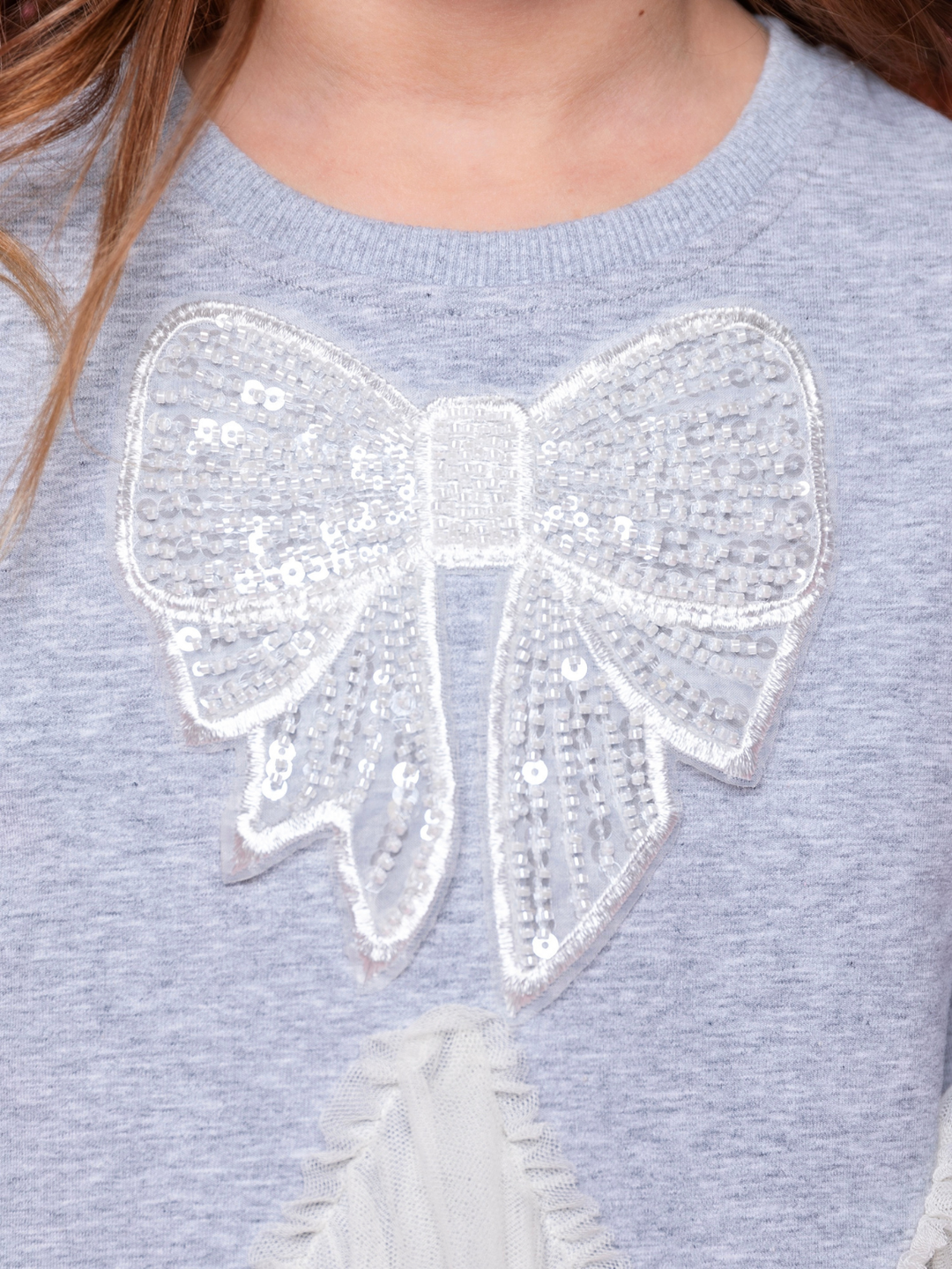 Close up of sequin bow detail on grey knit dress