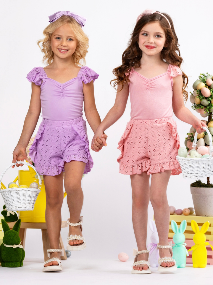 Girl wearing a coral eyelet Easter short set with ruffle shorts for spring celebrations
