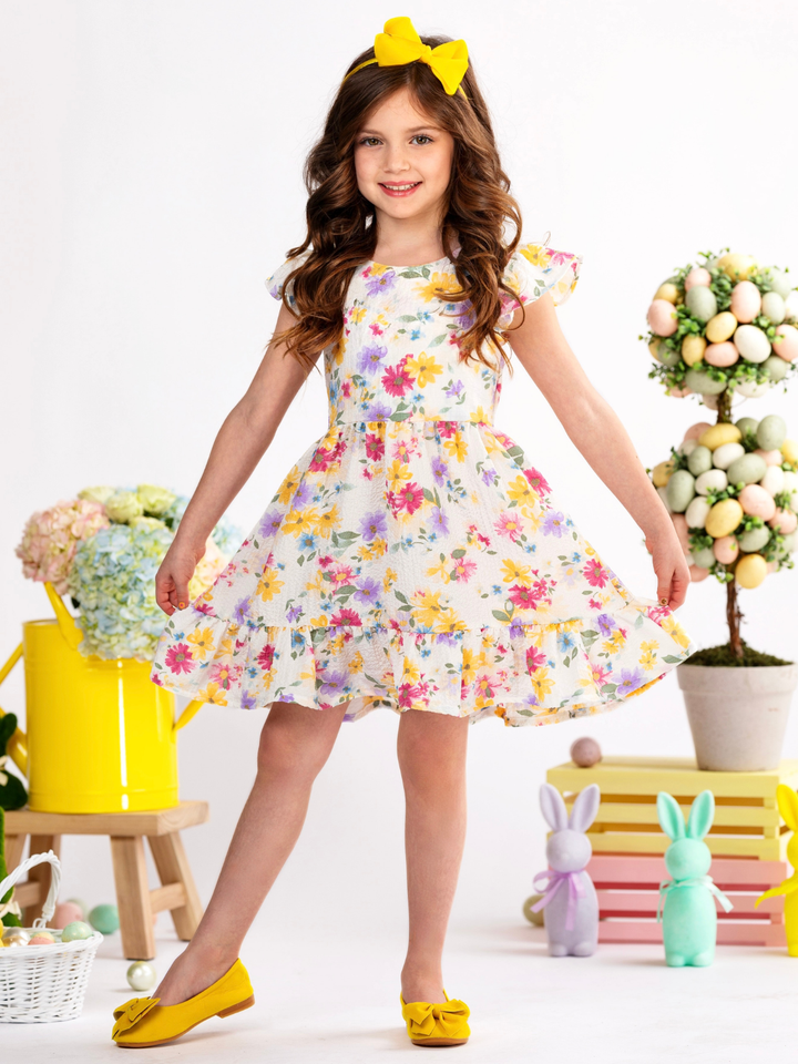 Girl wearing a floral Easter dress with flutter sleeves and bow back detail