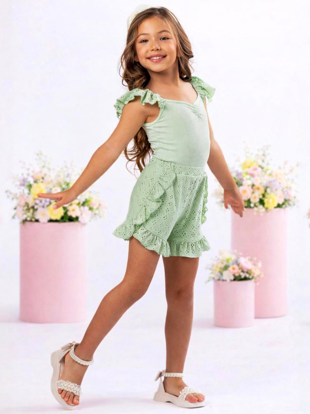 Girl wearing a sage eyelet short set with ruffle shorts for spring celebrations
