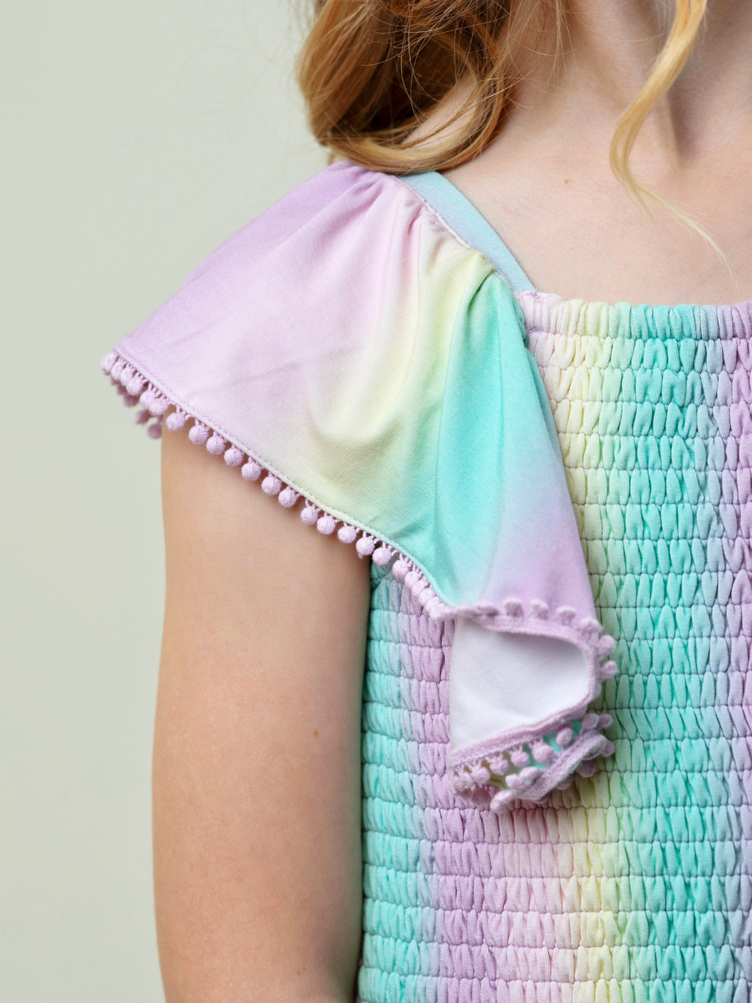 girls rainbow smocked romper with pom pom sleeves