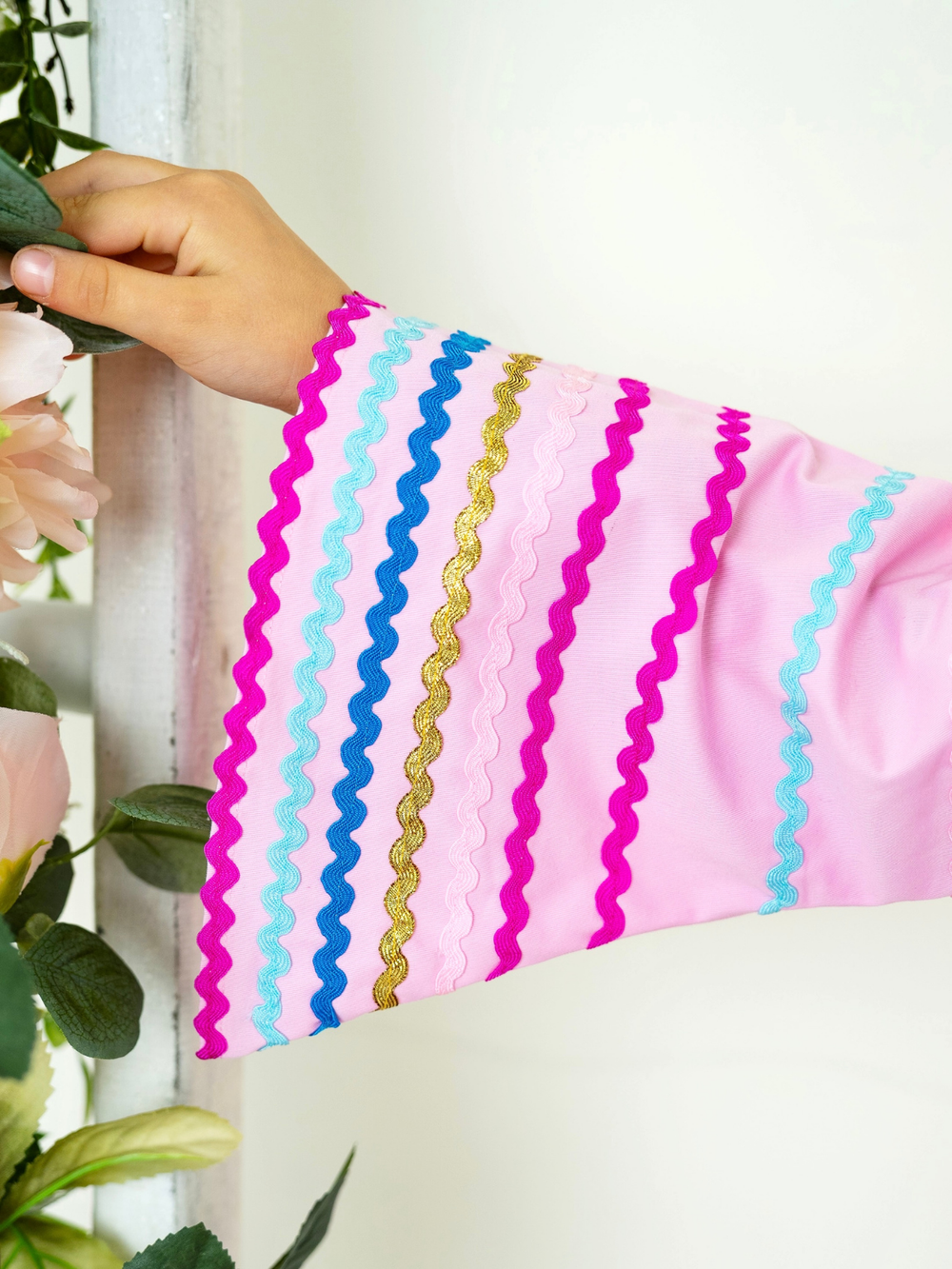 Close up of colorful ric rac trim on girls pink sleeve