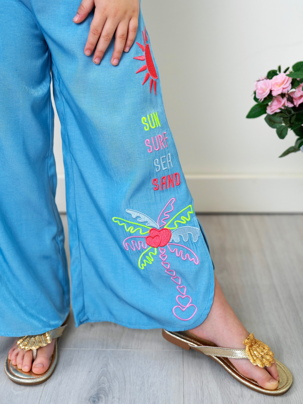 Close up of girls beach pants with sun surf sea sand embroidery