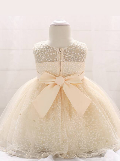 Baby dress has a tulle overlay with embroidered stars with an attached pearl belt and bow at the back-beige