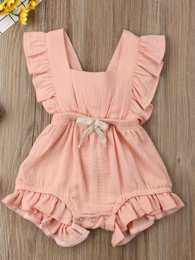 Baby bohemian Overall style romper onesie that ties in the back and has a drawstring at the waist. Little ruffled adorn the shoulder and short hem pink