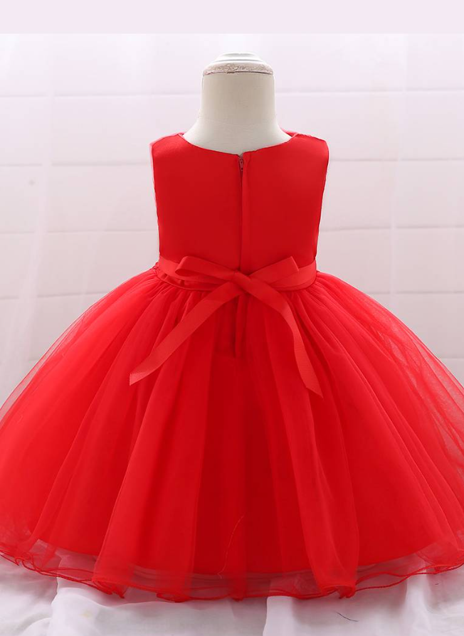 Baby dress has a tulle overlay with flower applique and a satin belt with rhinestone detail-red