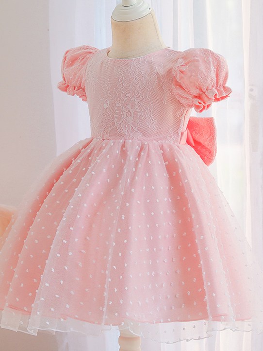 Baby dress has capped sleeves and embroidered tulle overlay bodice and swiss tulle overlay skirt, big bow accent at the back