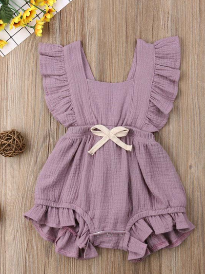 Baby bohemian Overall style romper onesie that ties in the back and has a drawstring at the waist. Little ruffled adorn the shoulder and short hem lilac