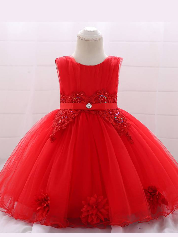 Baby dress has a tulle overlay with flower applique and a satin belt with rhinestone detail-red