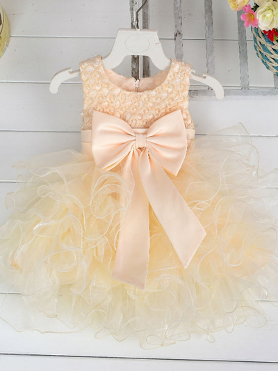 Baby princess dress has a satin bodice with pearl details, a bow belt at the waist, and a layered tulle skirt -creme