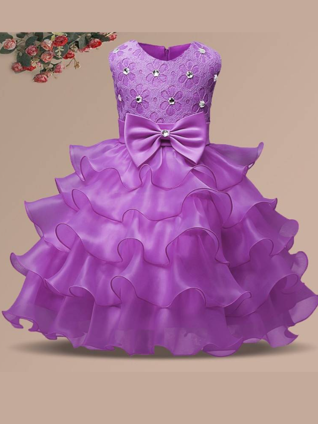 Baby princess dress has a floral lace bodice with rhinestone details, a bow belt at the waist, and a multi-layered tulle skirt-lilac