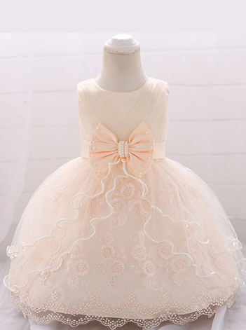 Baby dress has a tulle overlay with a multi-layer skirt, bow detail at the waist-creme