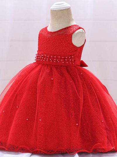Baby dress has a tulle overlay with embroidered stars with an attached pearl belt and bow at the back-red