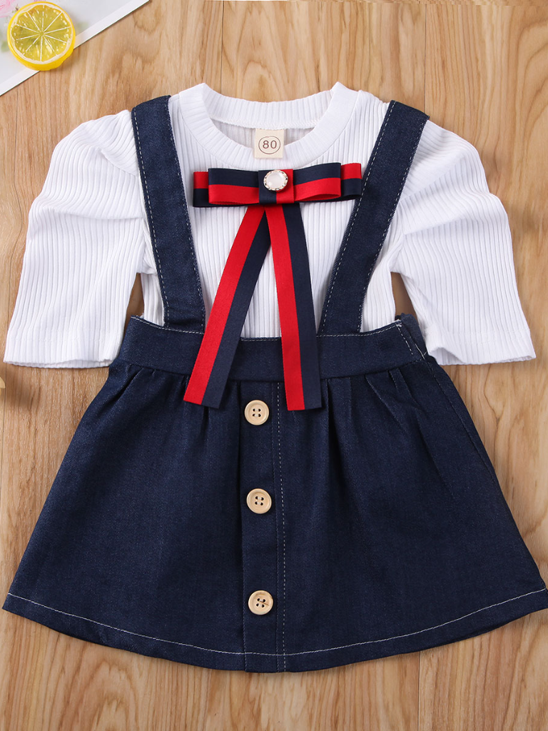Girls set features a white top with a red/blue bow and a denim suspender skirt