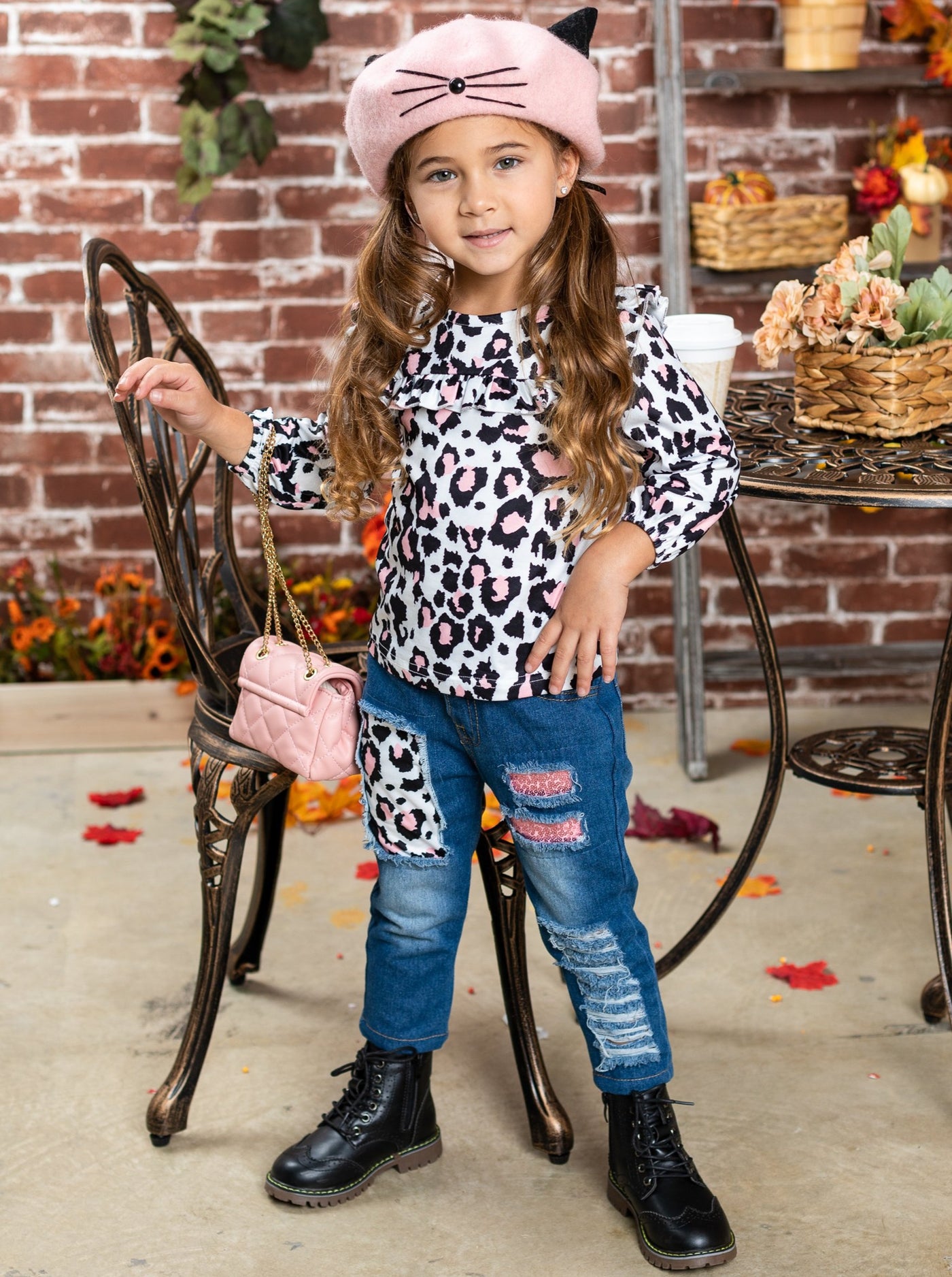 Girls set features a ruffled long-sleeved top with cow print and patched, distressed jeans with sash