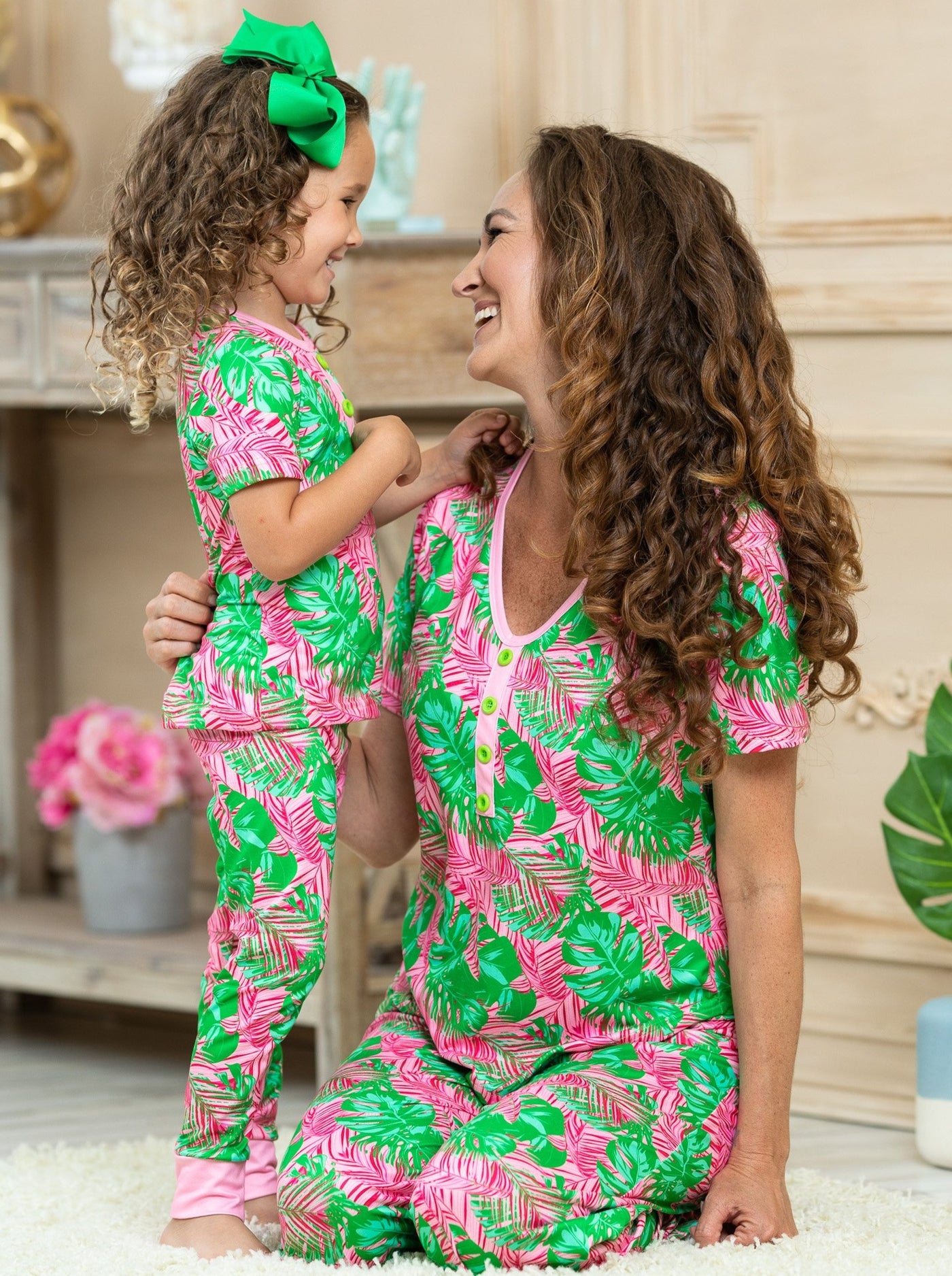 short leeved pink pajamas feature pink/green palm leaf prints, 3 front buttons, and pink cuffs on the kid version 