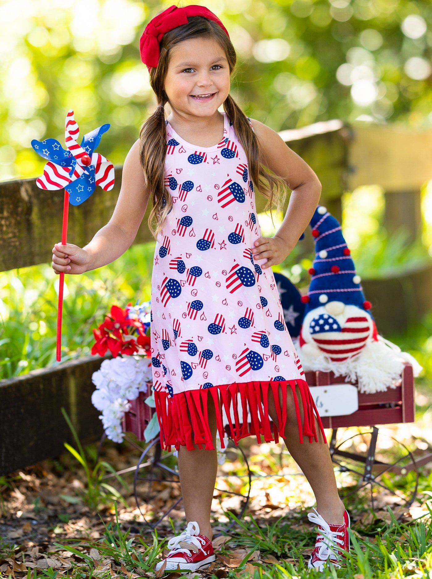 Girls pink dress features an Americana print with fun fringes at the hem