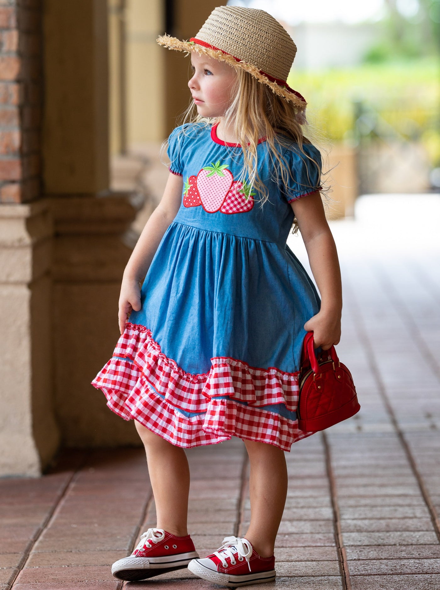girls denim dress has a strawberries applique and red and white plaid ruffles