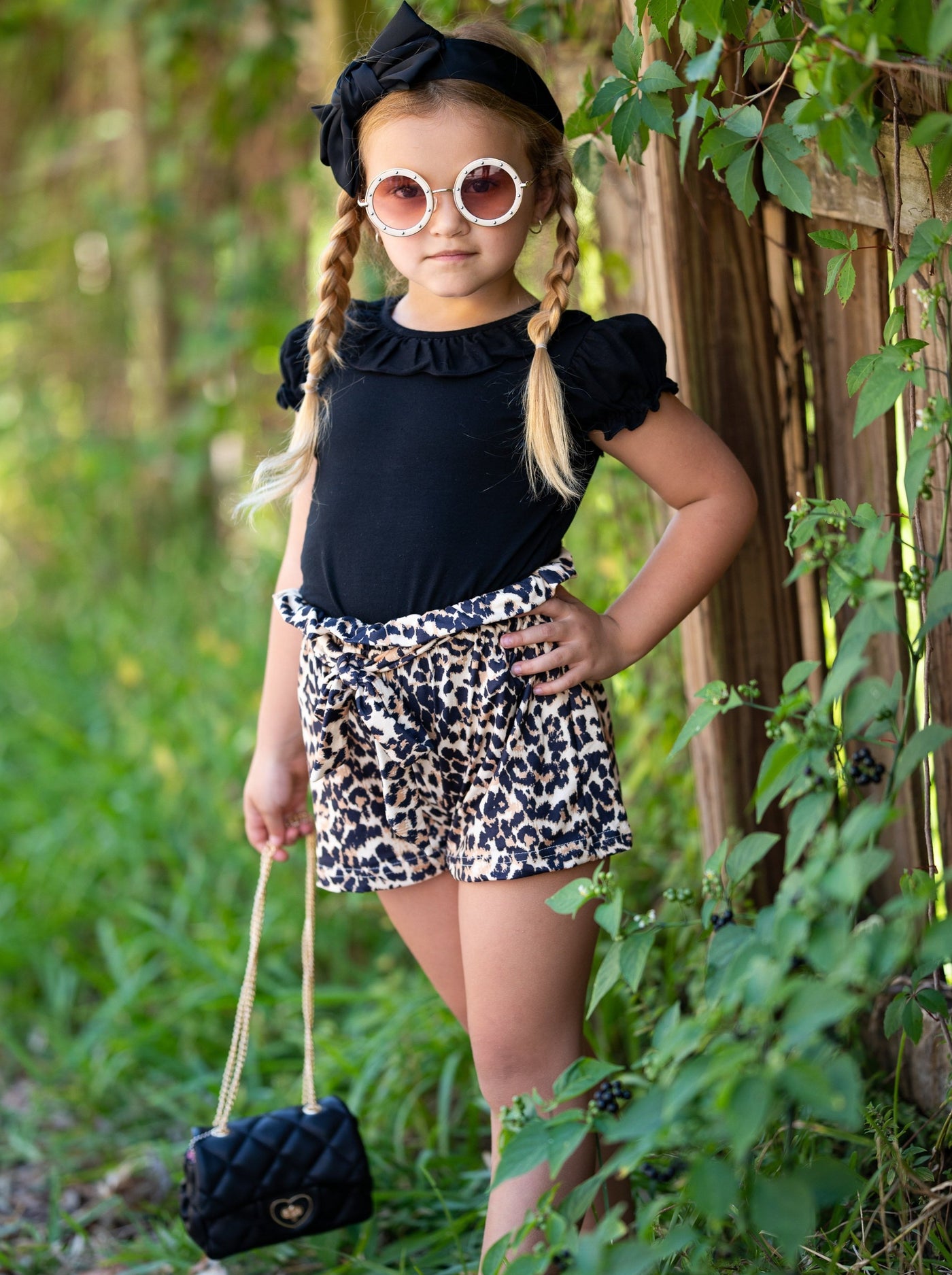 girls set features a black top with a bib and ruffled short sleeves and leopard printed shorts with a sash