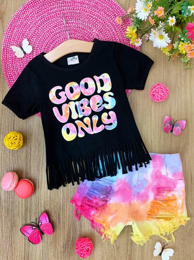Girls set features a black top with fringes at the hem and a tie-dye "Good Vibes Only" text graphic and matching tie-dye denim shorts