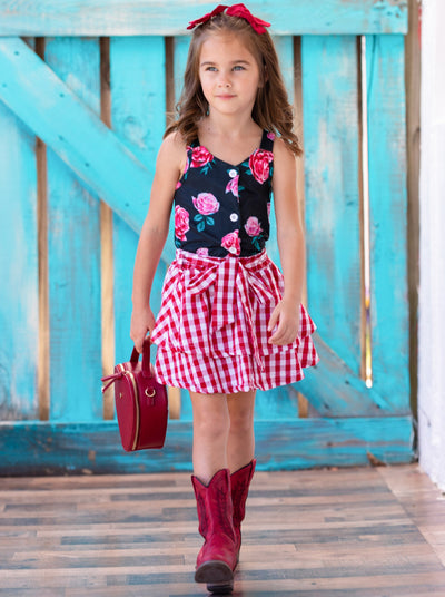 Girls set features a black floral sleeveless faux button-down top and a checkered two-tiered skirt with a sash at the waist