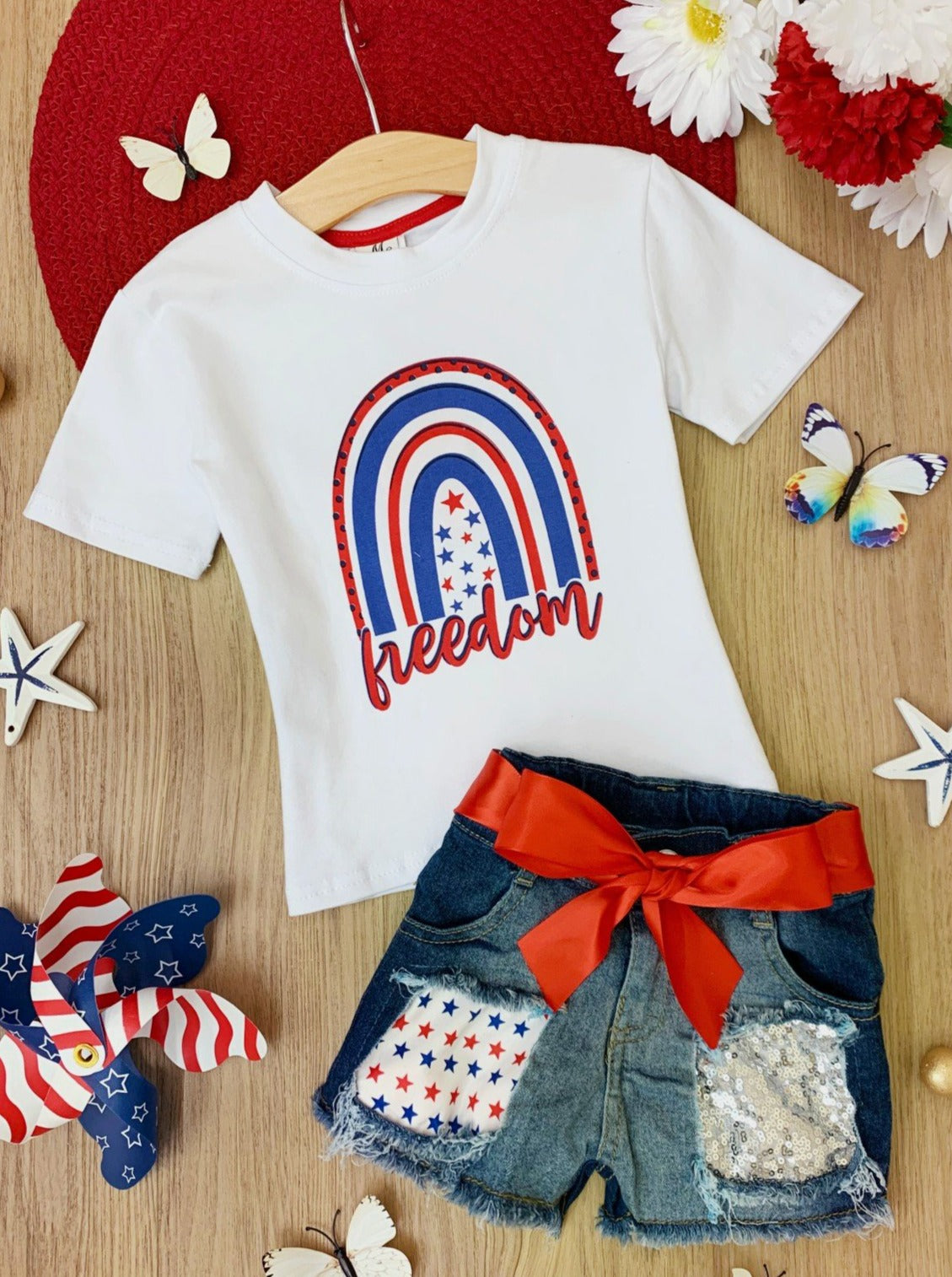 Girls set features a white top with "Freedom" print and patched denim shorts with a red sash