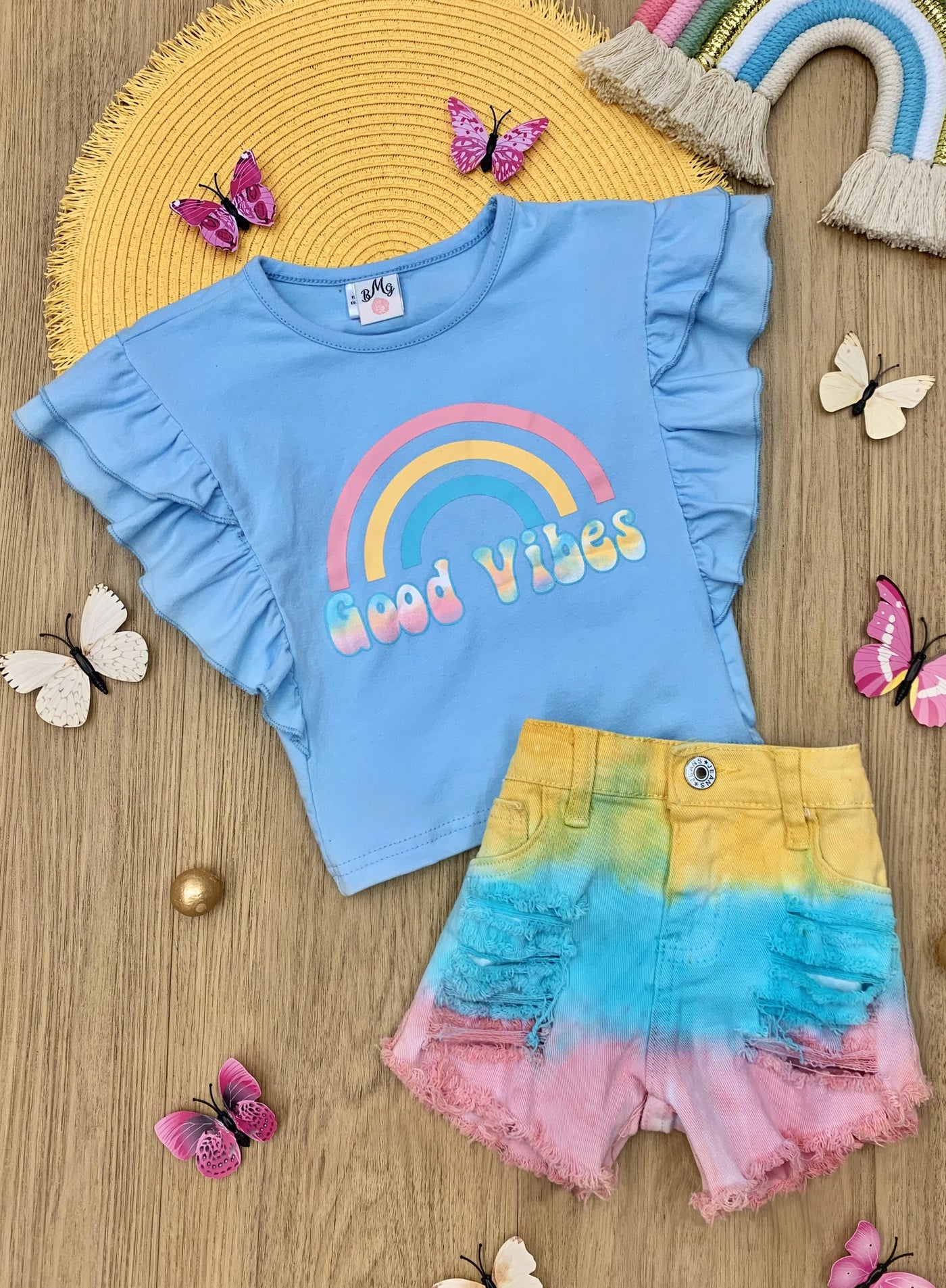 Girls set features a light blue ruffled top with "Good Vibes" graphics and tie-dye denim short