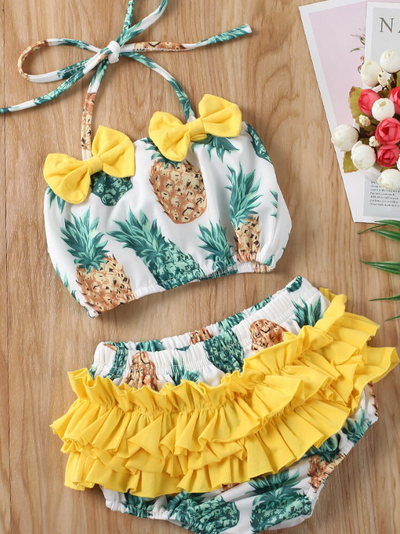 Baby swimsuit features a top with a fruit print and an adjustable halter style strap with ruffles bottoms