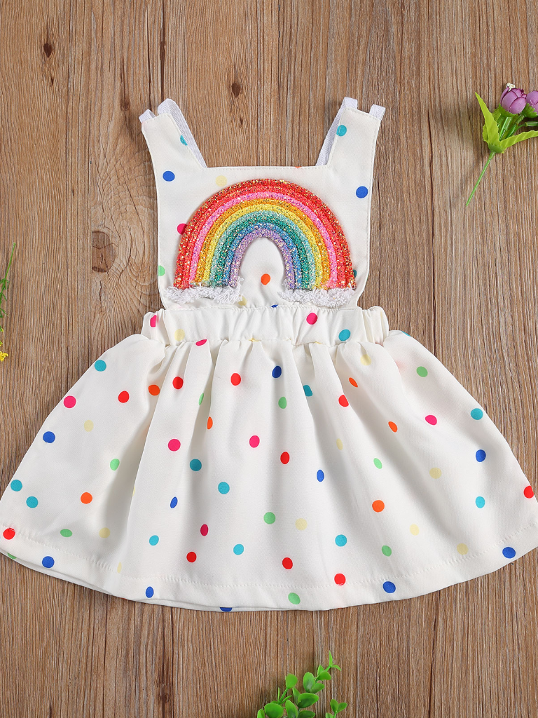 Baby white dress has a colorful polka dot print and rainbow applique pullover style ties at the back