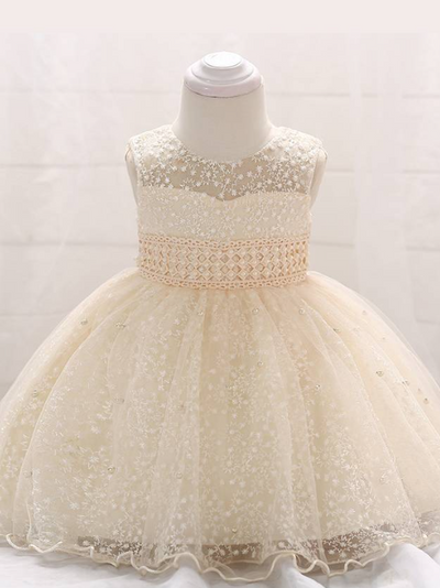 Baby dress has a tulle overlay with embroidered stars with an attached pearl belt and bow at the back-beige