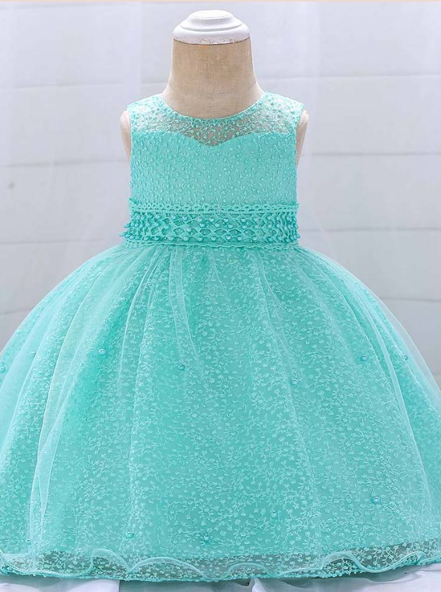 Baby dress has a tulle overlay with embroidered stars with an attached pearl belt and bow at the back-turquoise