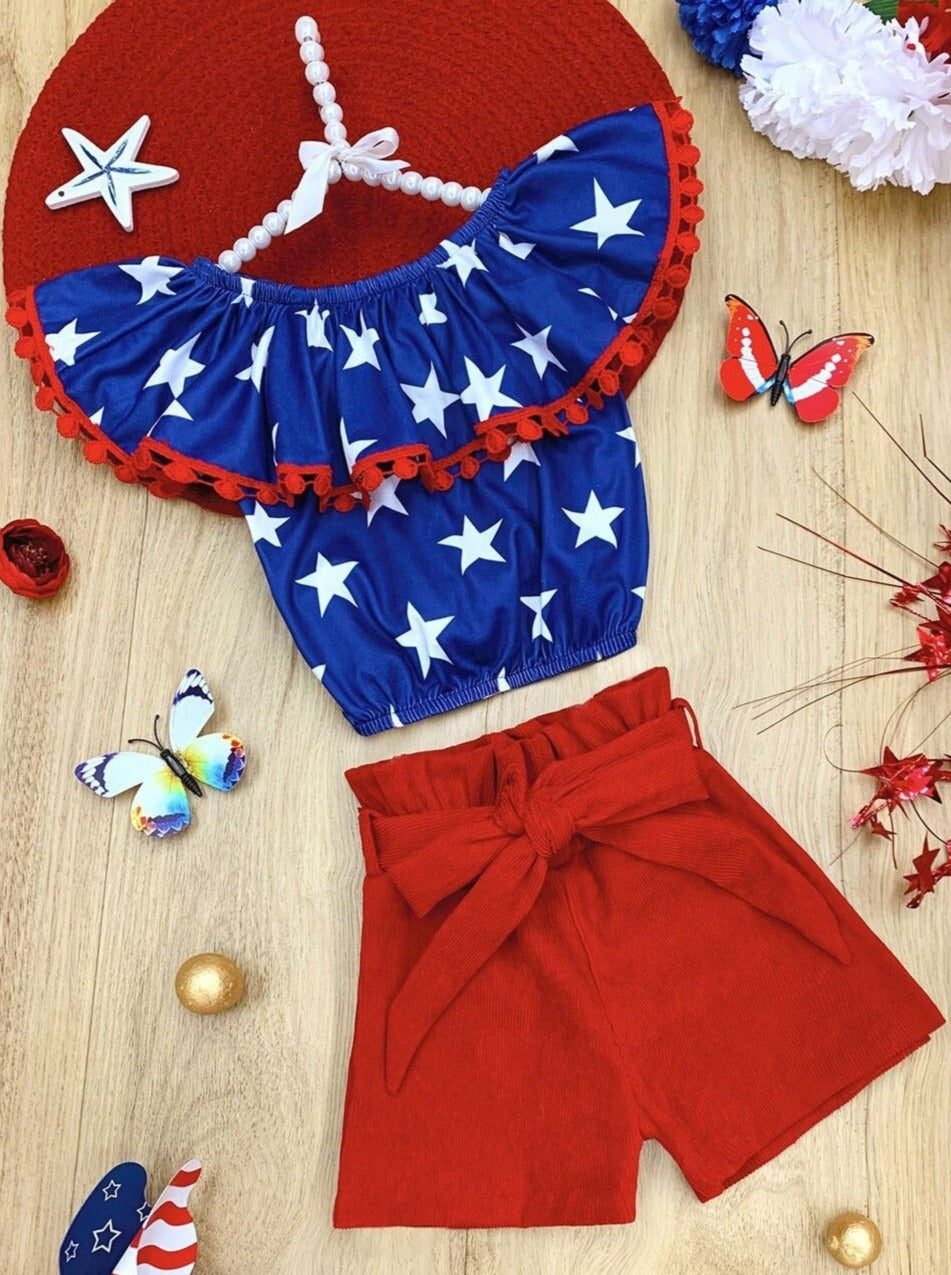 Girls set features a blue top with white star print and oversized bib, comes with red shorts with sash